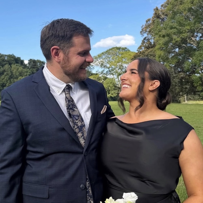Kelly and Dean smiling at each other in a sunny field